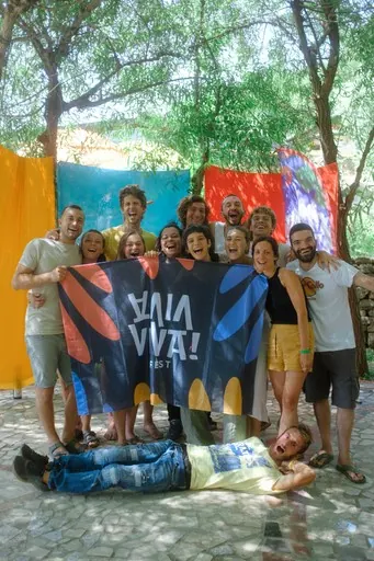 Un gruppo in posa con la bandiera del Viva Viva, e un ragazzo sdraiato per terra davanti a tutti