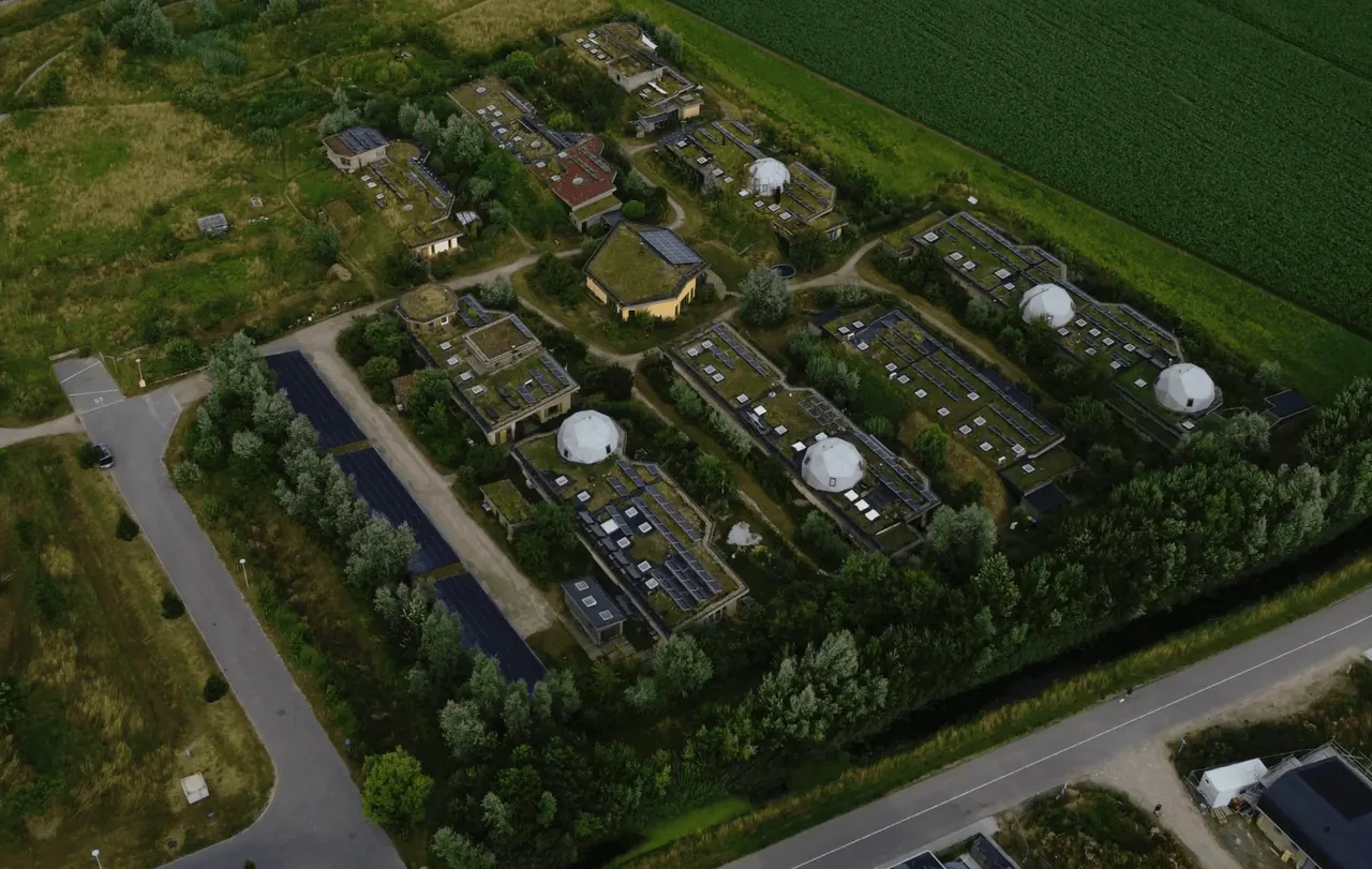 Un villaggio visto dall'alto: case basse coi tetti verdi e le cupole, in mezzo ai campi
