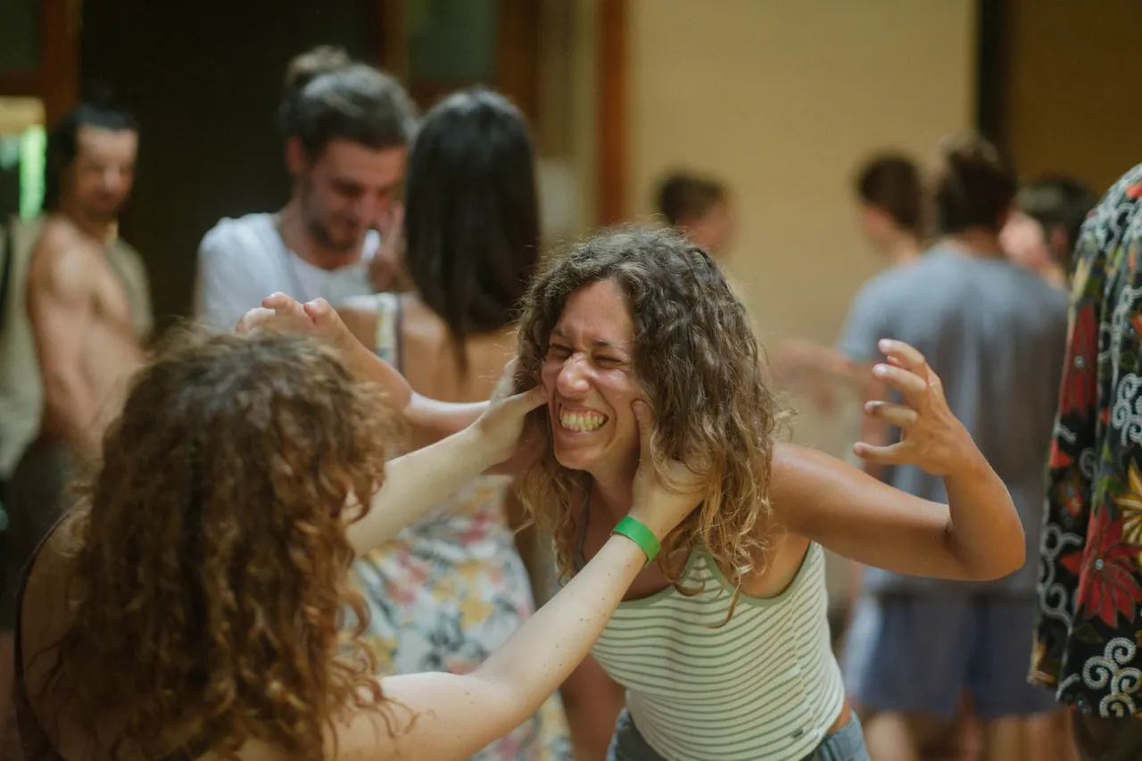 Due ragazze giocano e ridono: una tiene il viso dell'altra fra le mani