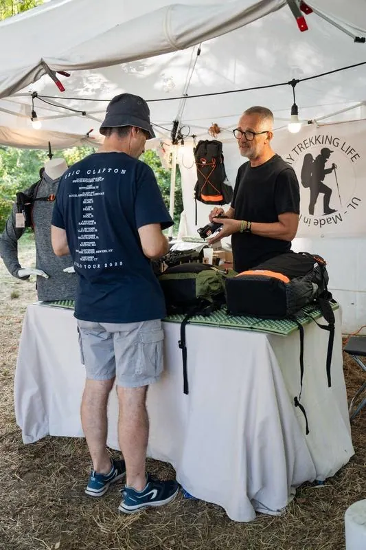 Uno stand di attrezzatura da trekking: chi lo gestisce mostra un prodotto a un partecipante